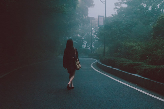 Eine Frau läuft auf einer leeren Straße in diesigem Wetter.
