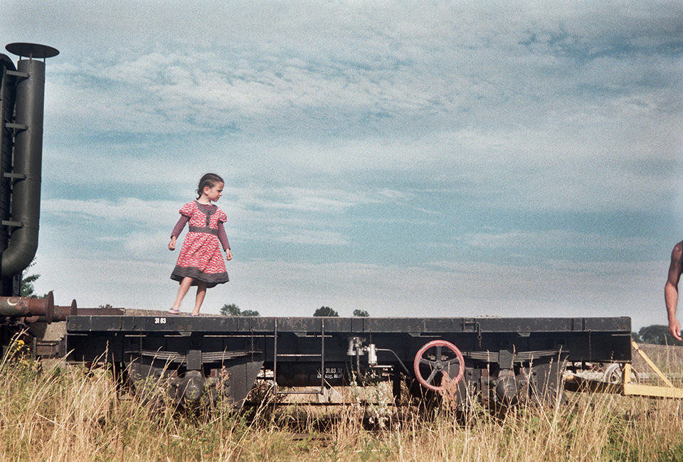 Ein Kind steht auf einem alten Lastenzug. Sommer.