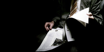 In der Dunkelheit Zeitung lesender Mann mit Anzug und Krawatte.