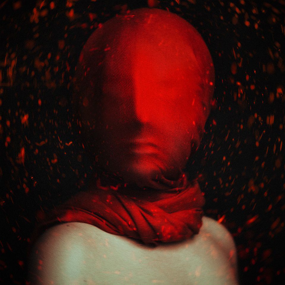 Mensch mit einem roten Tuch eng um den Kopf und von roten, flirrenden Lichtern umgeben.
