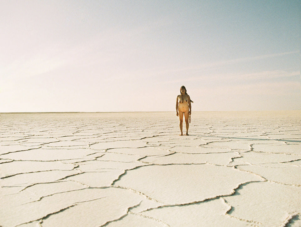 Eine Frau steht nackt in der Wüste.