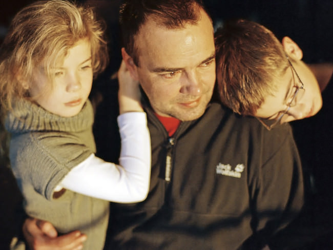 Ein Vater mit zwei Kindern auf dem Arm. 