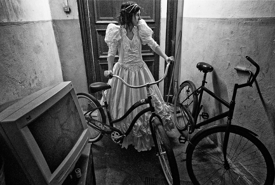 Eine Frau im Bruatkleid steht mit einem Fahrrad im Hausflur.