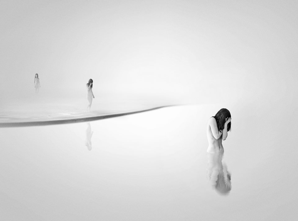 Eine Frau geht in einer weißen surrealen Landschaft ins Wasser