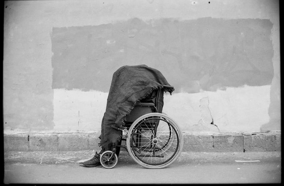 Eine Person in einem Rollstuhl ist von einer Decke bedeckt.