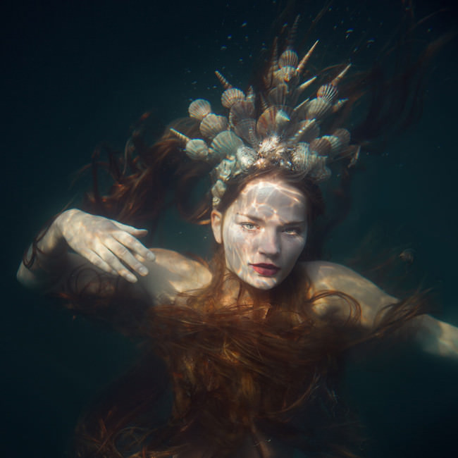 Eine Meerjungfrau mit Muschelkrone Unterwasser.