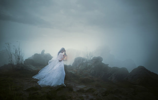 Eine Frau im Nebel mit Laterne.