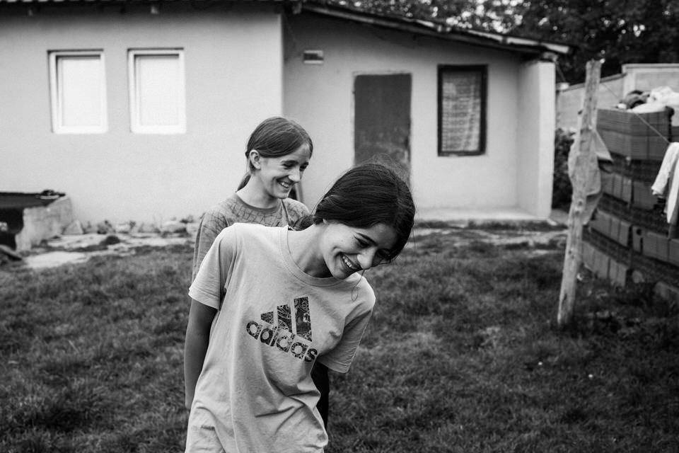 Zwei Mädchen im Hof lachen verschmitzt. 