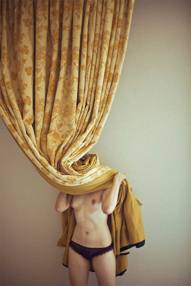 Eine Frau versteckt sich hinter dem Vorhang.