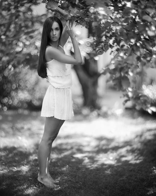 Eine Frau im weißem Kleid an einem Baum