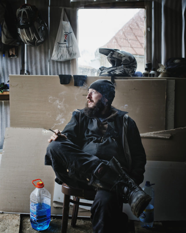 Ein rauchender Mann in schwarzer Kleidung schaut aus einer Garage. 
