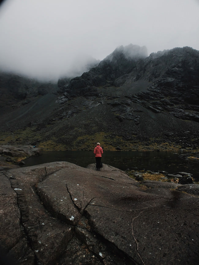 Landschaftsfoto aus Schottland mit einer Person in roter Jacke.