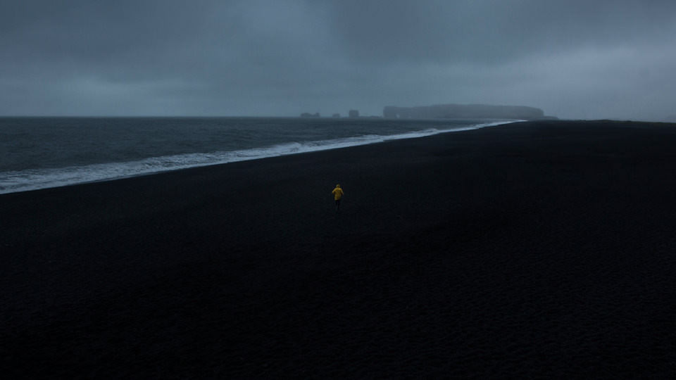 Ein Mann mit gelber Regenjacke am Strand