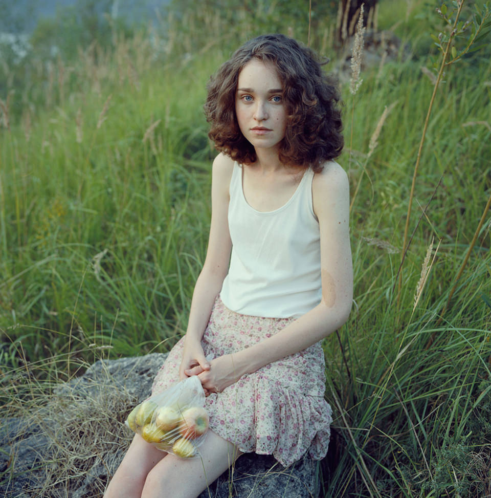 Eine Frau sitzt mit einer Tüte Äpfeln auf einem Stein