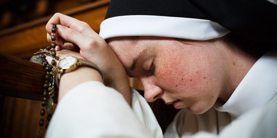 Eine betende Nonne mit Rosenkranz in der Hand.