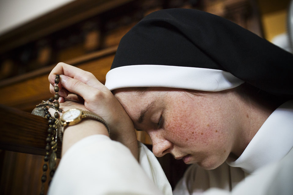 Eine Nonne beim Beten mit  dem Rosenkranz. 