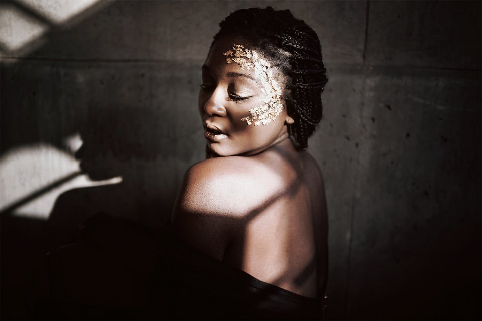 Portrait einer Frau mit Blattgold im Gesicht, Schattenspiel auf ihrer Haut.