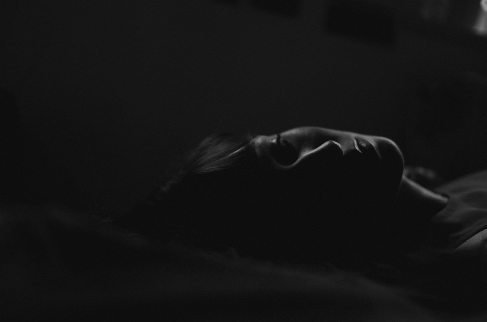 Lowkey-Portrait einer Frau in der Dunkelheit, liegend.