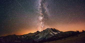 Nachthimmel mit Milchstraße üder einer Berglandschaft.