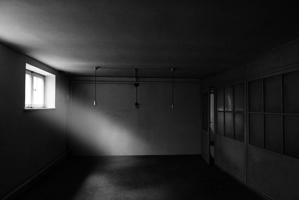 Ein dunkler Raum, in den etwas Licht durch ein kleines Fenster fällt.