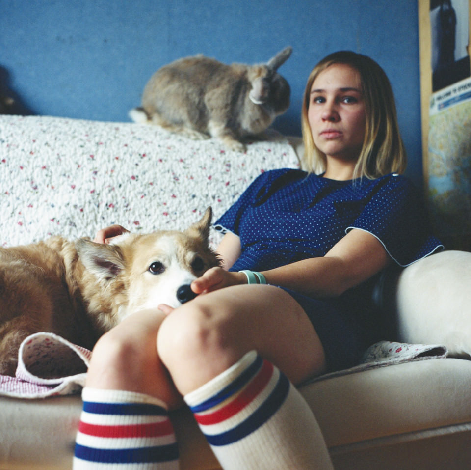 Eine junge Frau sitzt auf nem Sofa, daneben ein Hund und ein Kaninchen.