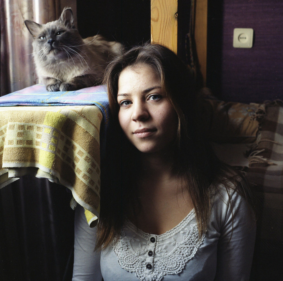 Eine junge Frau lehnt sich an einen Tisch mit einer Katze darauf.