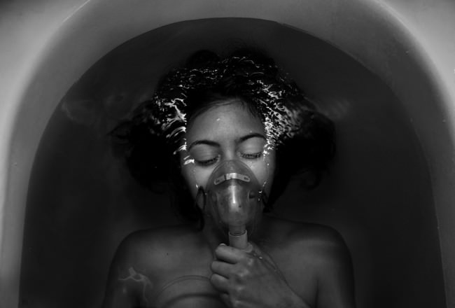 Eine Frau liegt in der Badewanne und trägt ein Sauerstoffgerät.