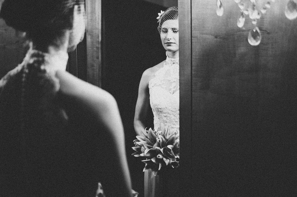 Eine Braut steht vor einem Spiegel und betrachtet sich darin.