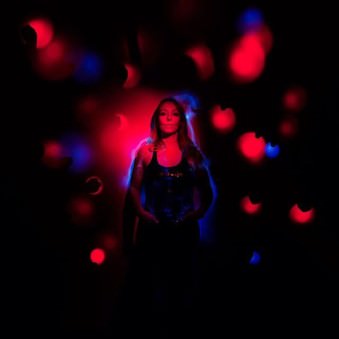 Eine Frau umgeben von roten und blauen Lichtern.