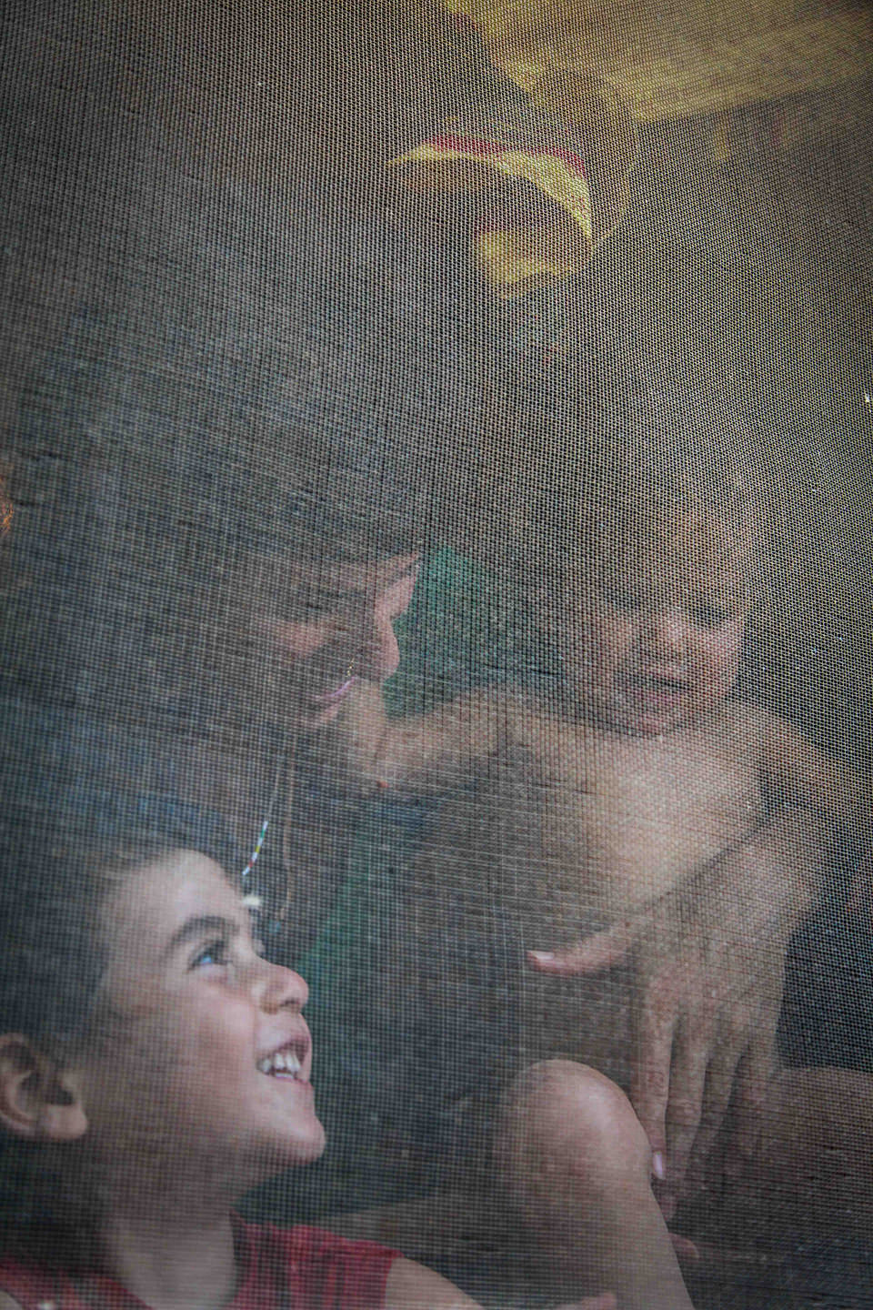 Eine Frau mit zwei Kindern hinter dünnem Stoff