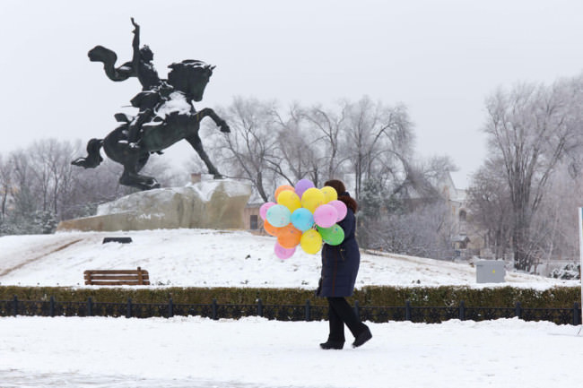 Eine Person trägt Luftballons vor einer Statute