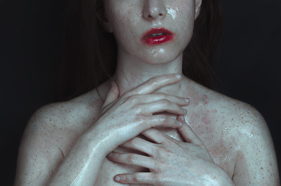 Eine nasse, nackte Frau trägt verschmierten Lippenstift.