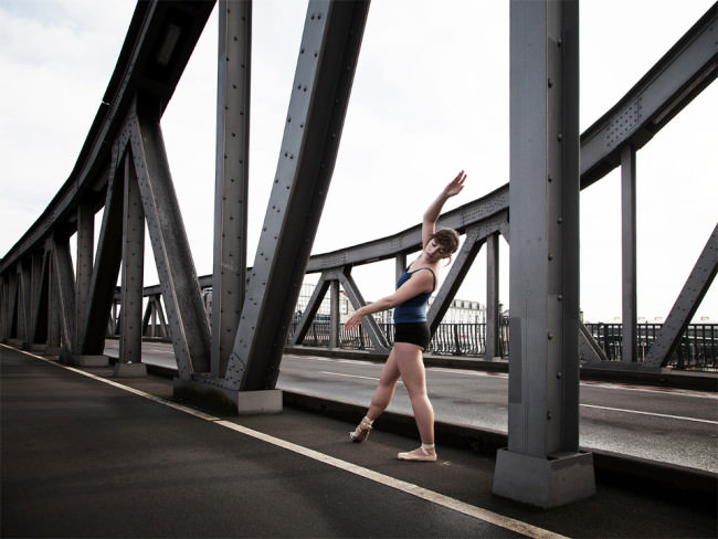 Eine Ballerina steht auf einer Brücke.