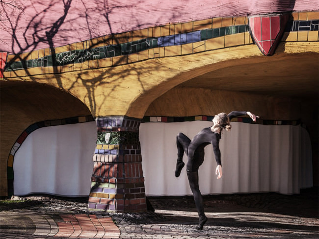 Eine Tänzerin verdreht ihren Körper unter einer Brücke.