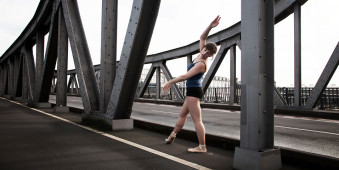 Eine Ballerina steht auf einer Brücke.
