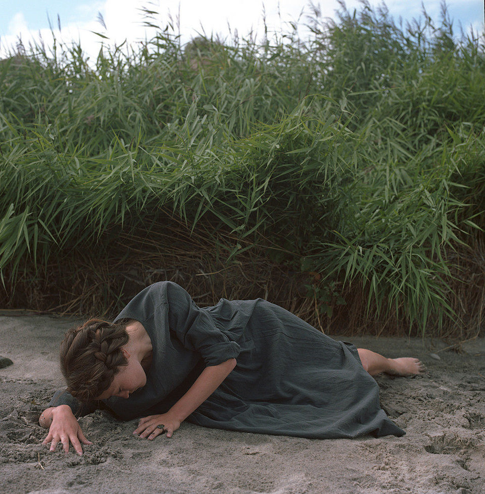 Eine junge Frau mit Zöpfen liegt auf dem Strand.
