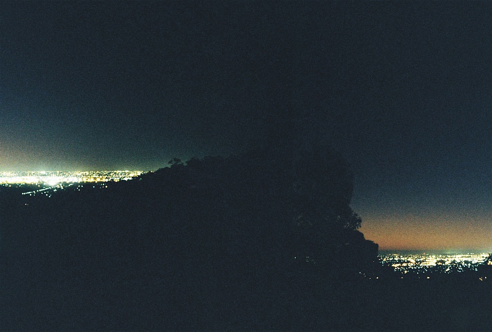 Lichter zweier Städte, nachts links und rechts eines Berges gelegen.