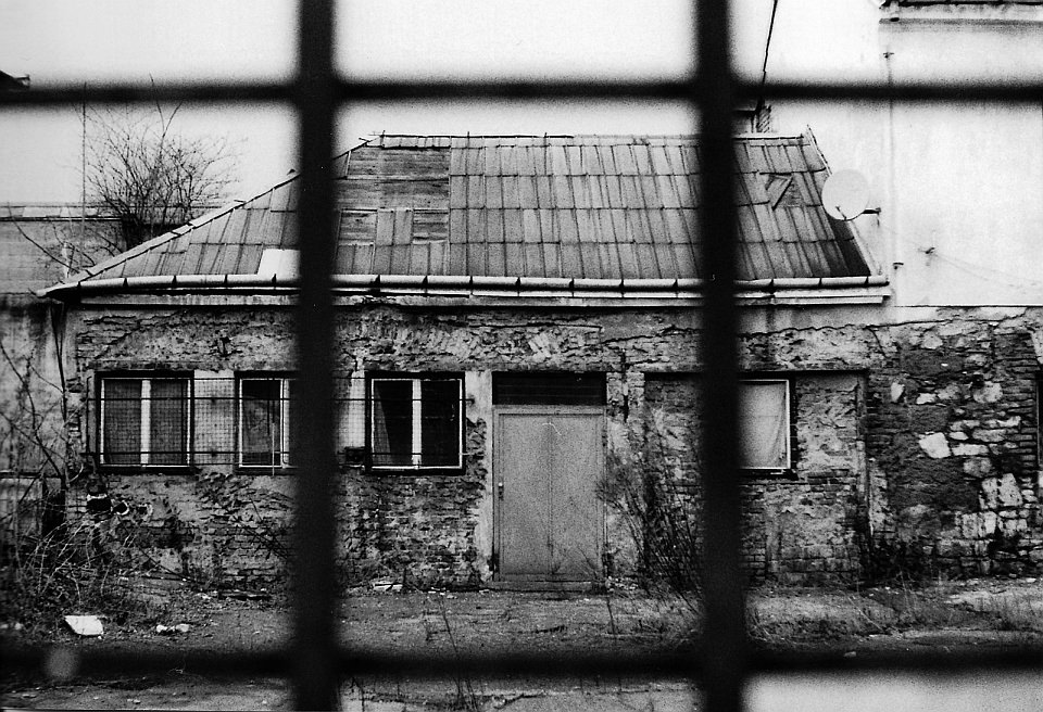 Schwarzweiß, Blick aus einem Fenster zu einem alten Haus.