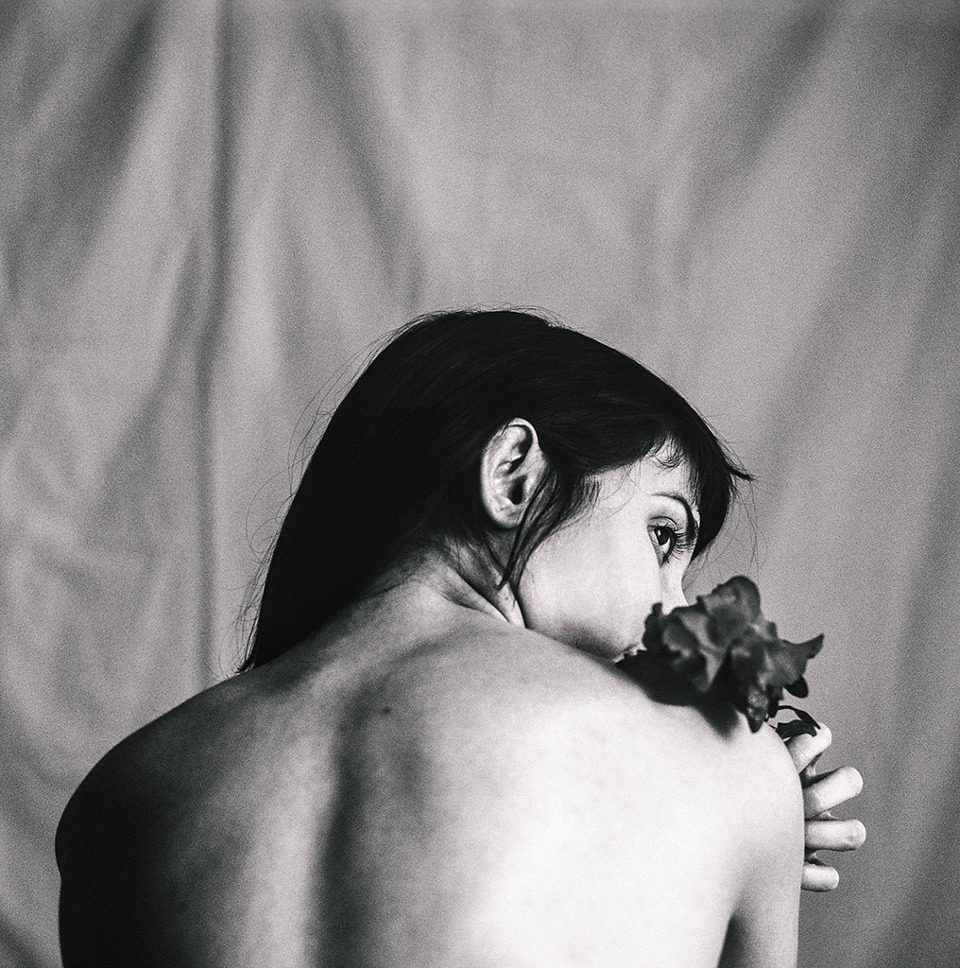 Schwarzweißfoto einer Frau mit Blumen auf den Schultern.