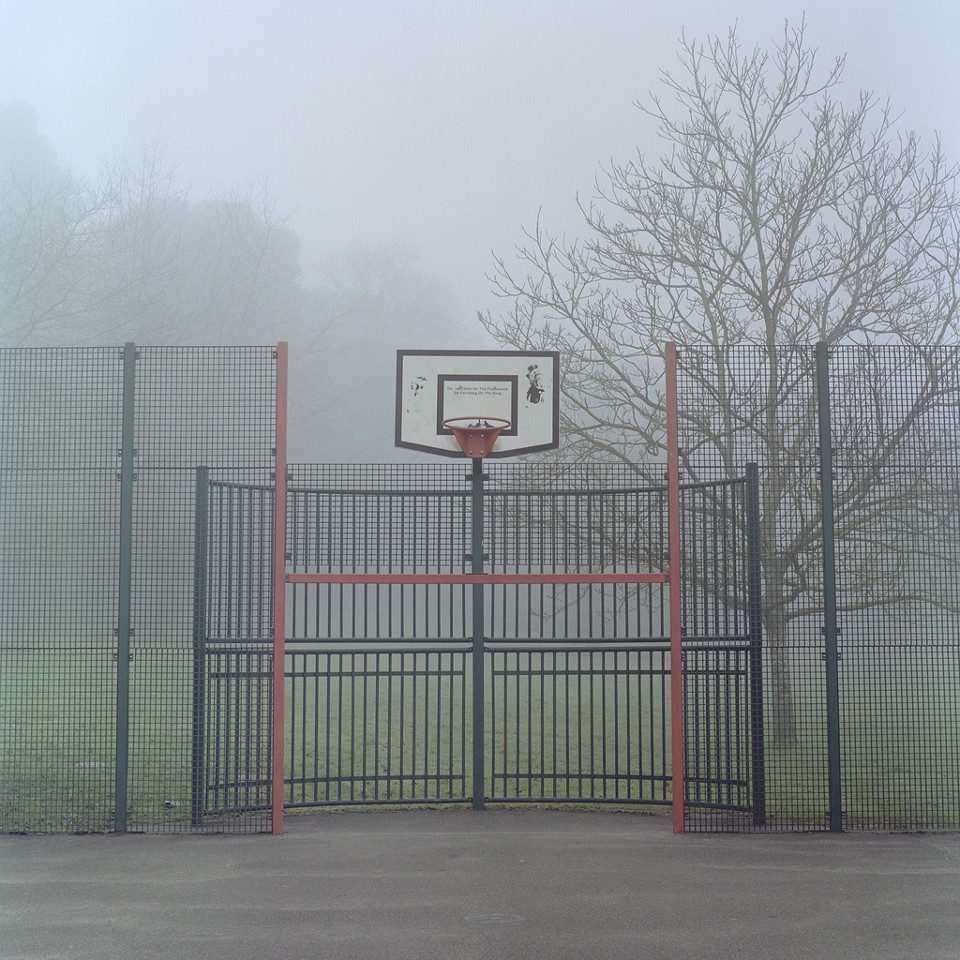Ein leeres Basketballfeld mit Korb liegt im Nebel.