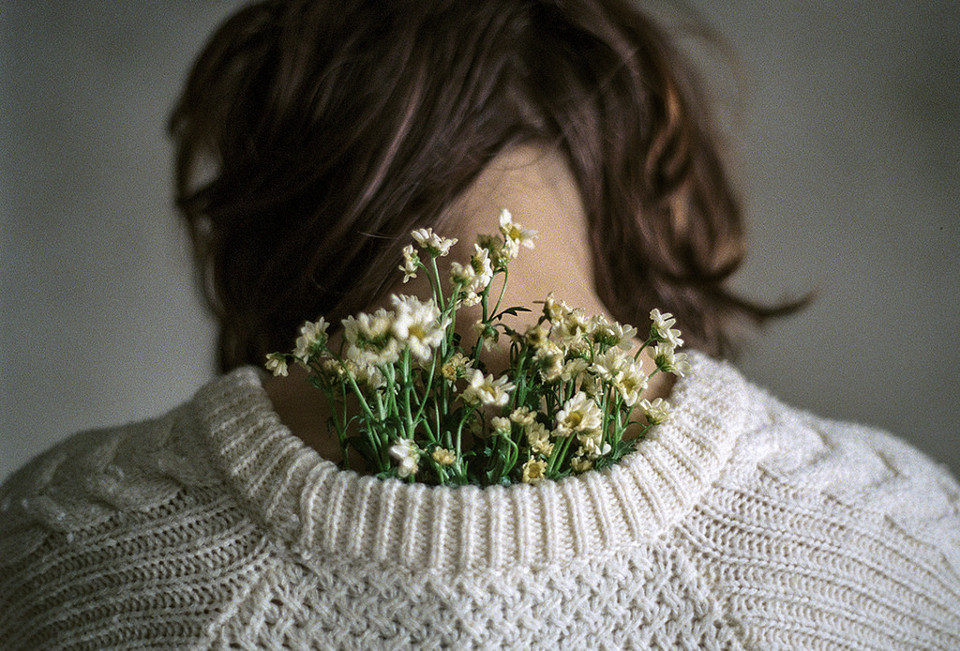Eine Frau hat einen Blumenstrauß im Pulloverausschnitt.