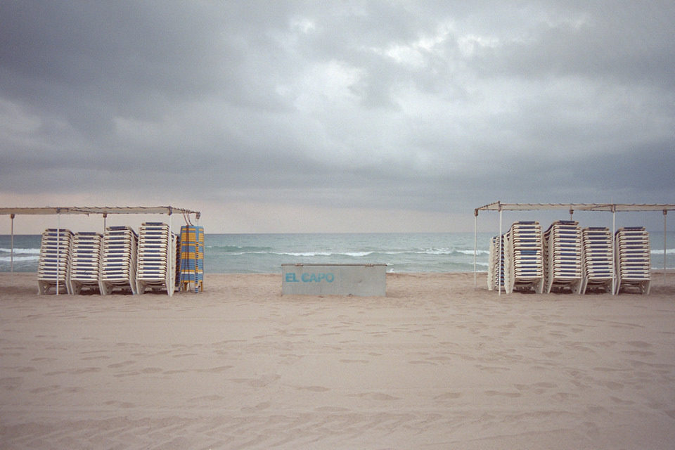 Badeliegen sind an einem leeren Strand gestapelt.