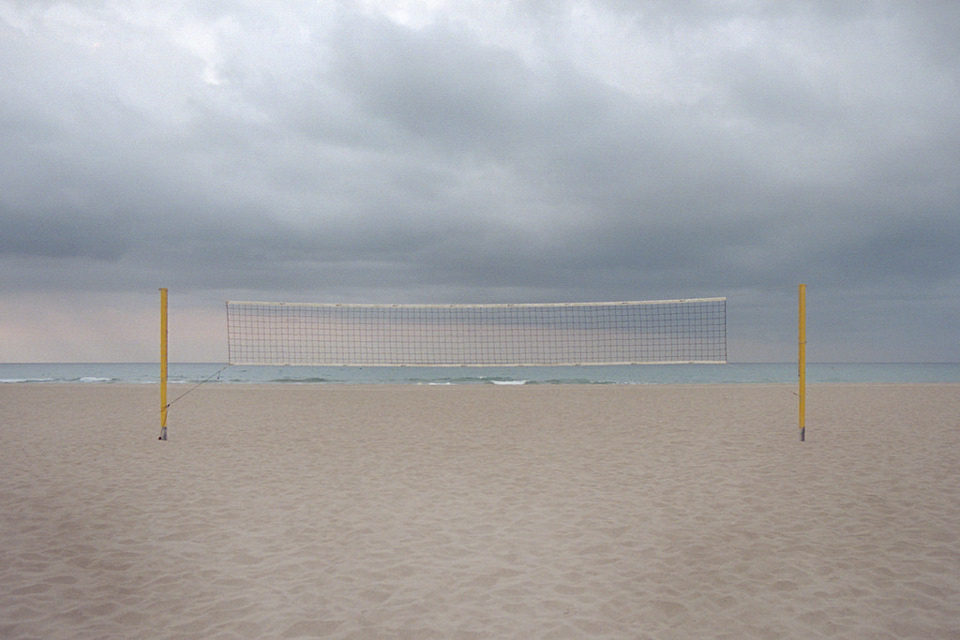 Ein Volleyballnetz steht an einem leeren Strand.