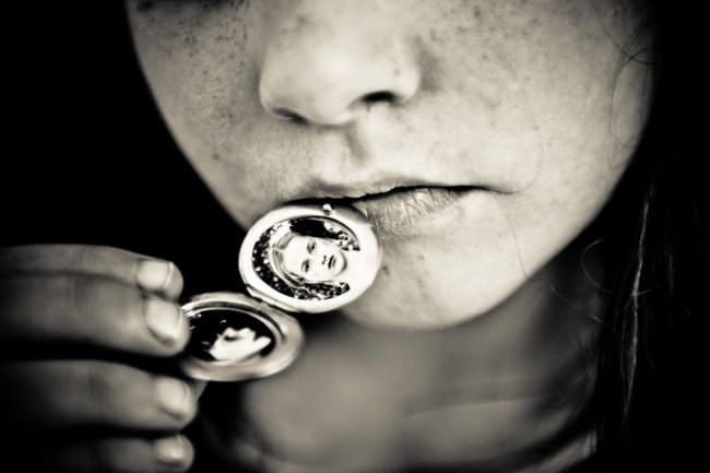 Bilder in einem Medaillon, das sich ein Mädchen an die Lippen hält.