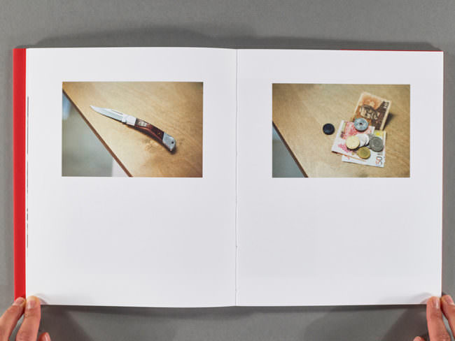 Aufgeschlagenes Buch mit 2 Fotografien aufgehalten von 2 Händen.