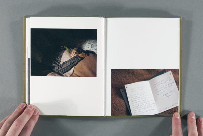 Aufgeschlagenes Buch mit zwei Fotografien, aufgehalten von zwei Händen.