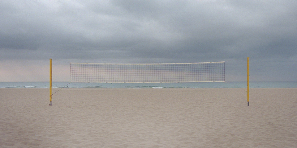 Ein Volleyballnetz steht an einem leeren Strand.