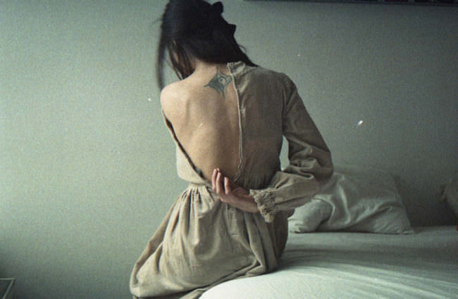 Eine Frau öffnet den Reißverschluss ihres Kleides und entblößt damit ihren Rücken.