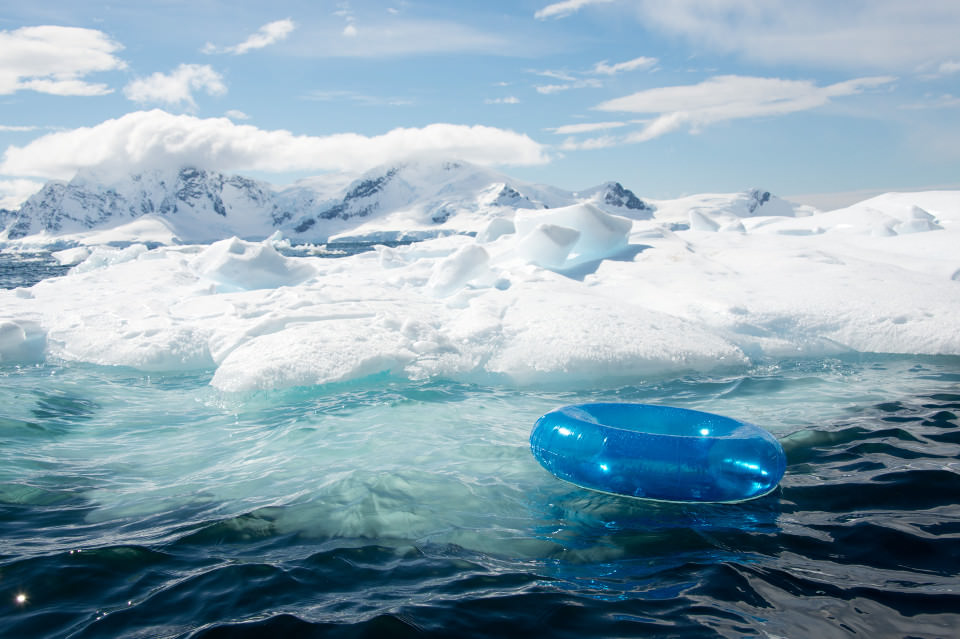 Ein blauer Schwimmreif treibt vor einer Eislandschaft.