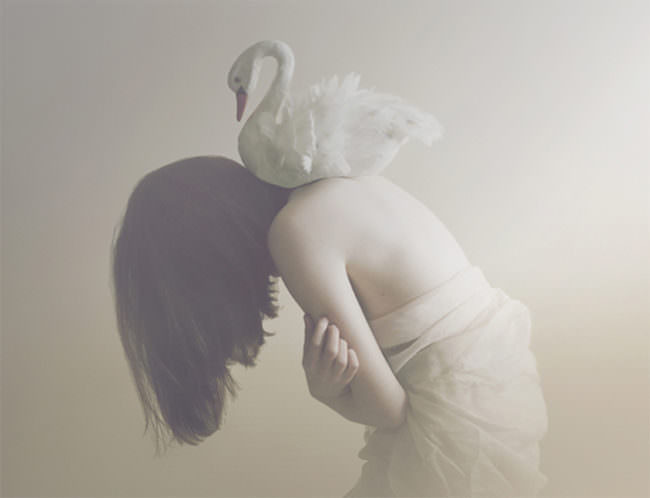 Ein Stoffschwan liegt auf den nackten Schultern eines Mädchens.